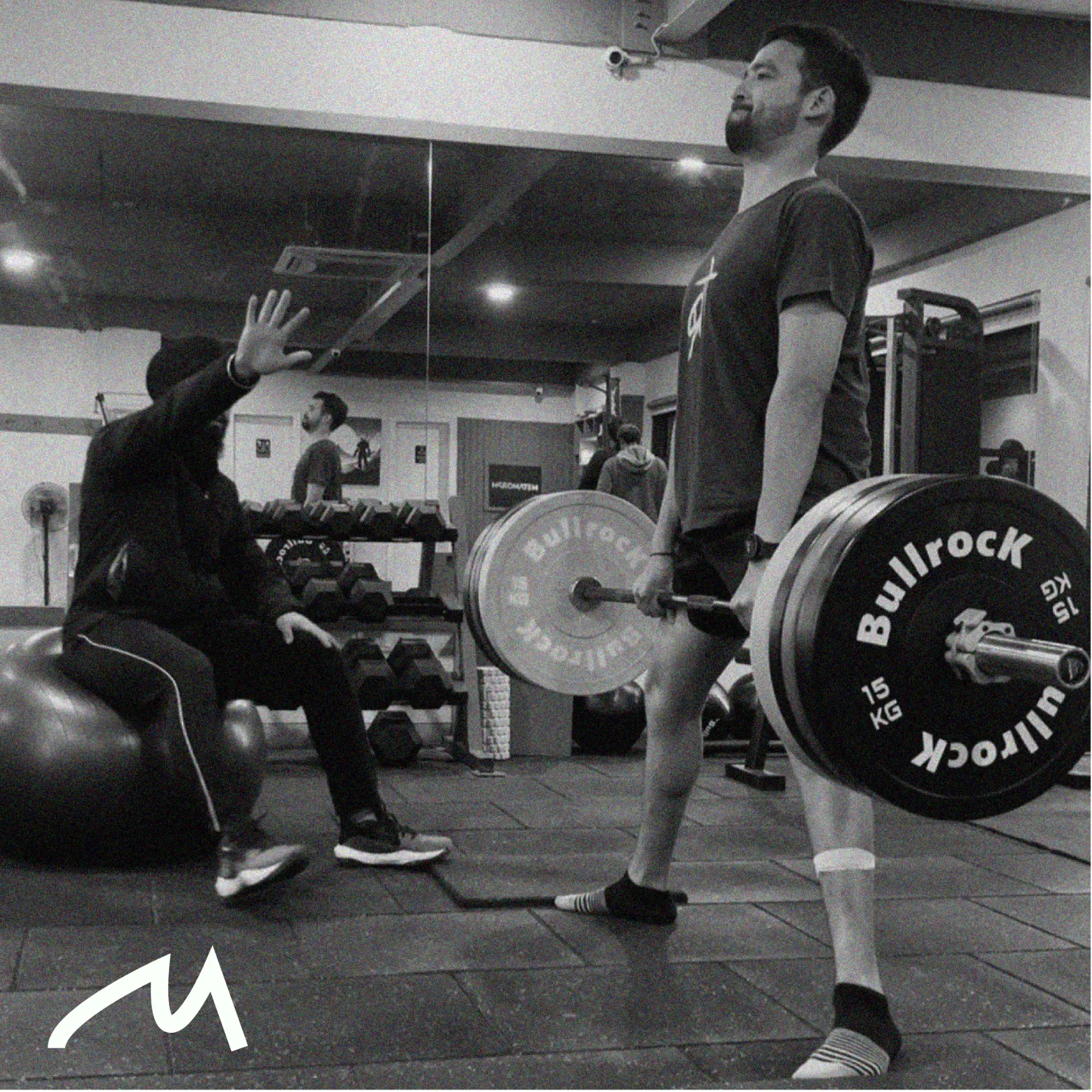 Black and white photo of a lifter at the top of a deadlift with the white Monk mark in the bottom left corner