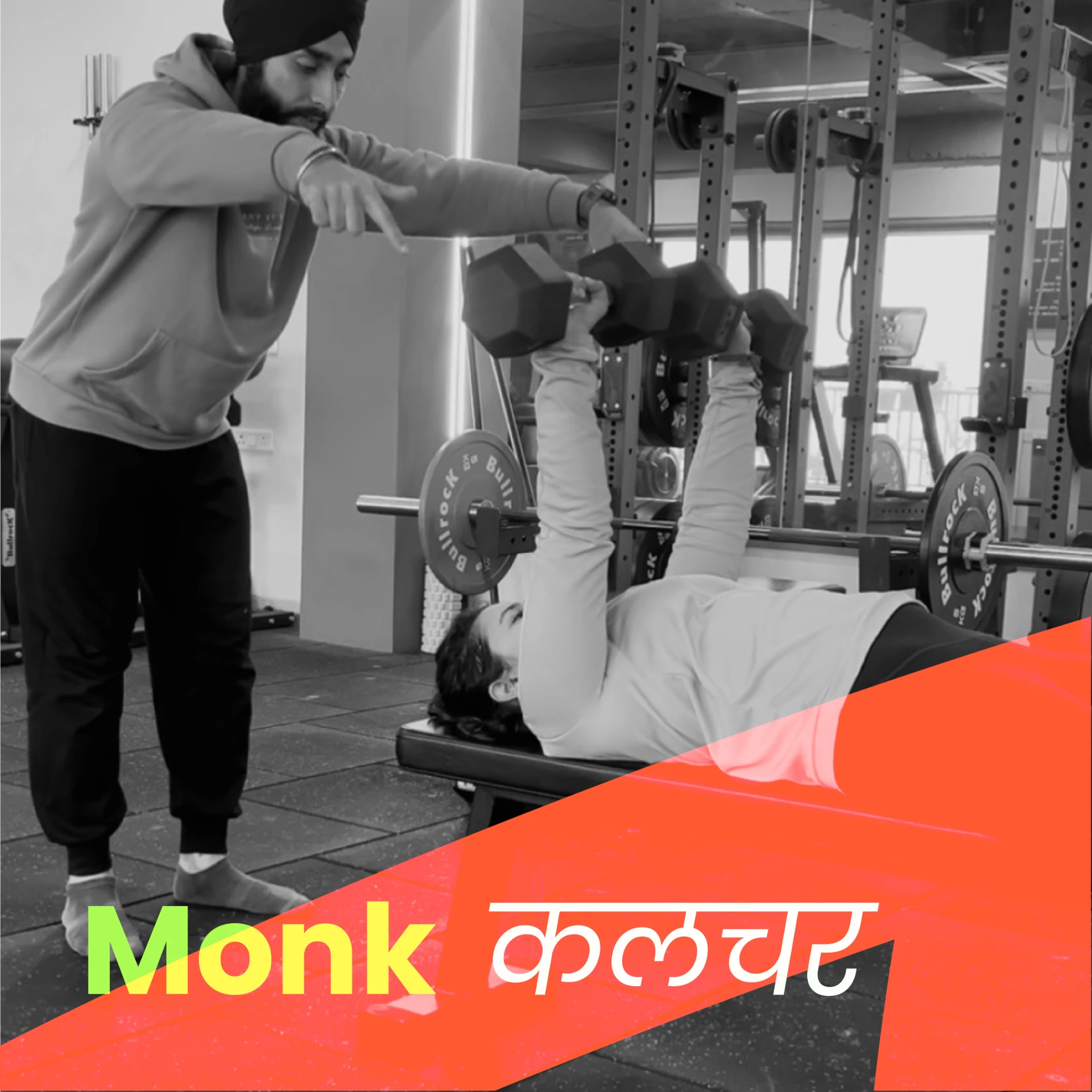 Black and white gym photo of a coach cueing a dumbbell press, overlaid with a red diagonal band reading Monk कलचर